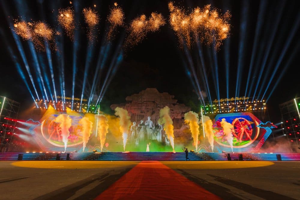 Sân khấu Đêm hội Thành Tuyên 2026 tại Quảng trường Nguyễn Tất Thành: phù điêu đá làm hậu cảnh, hai màn LED tạo hình đèn kéo quân, cột khói và pháo hoa trên nền trời đêm