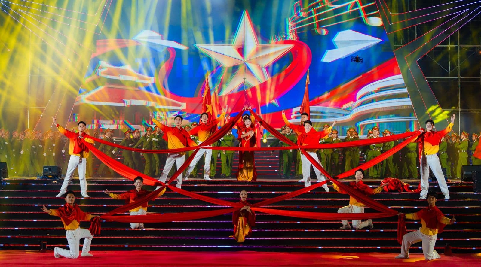Tiết mục múa trong concert Cao Bằng – Non nước ngàn năm: vũ công áo đỏ vàng căng những dải lụa đỏ thành hình ngôi sao, phía sau là khối diễn viên trong trang phục công an nhân dân, màn LED hình ngôi sao vàng và chùm đèn moving head