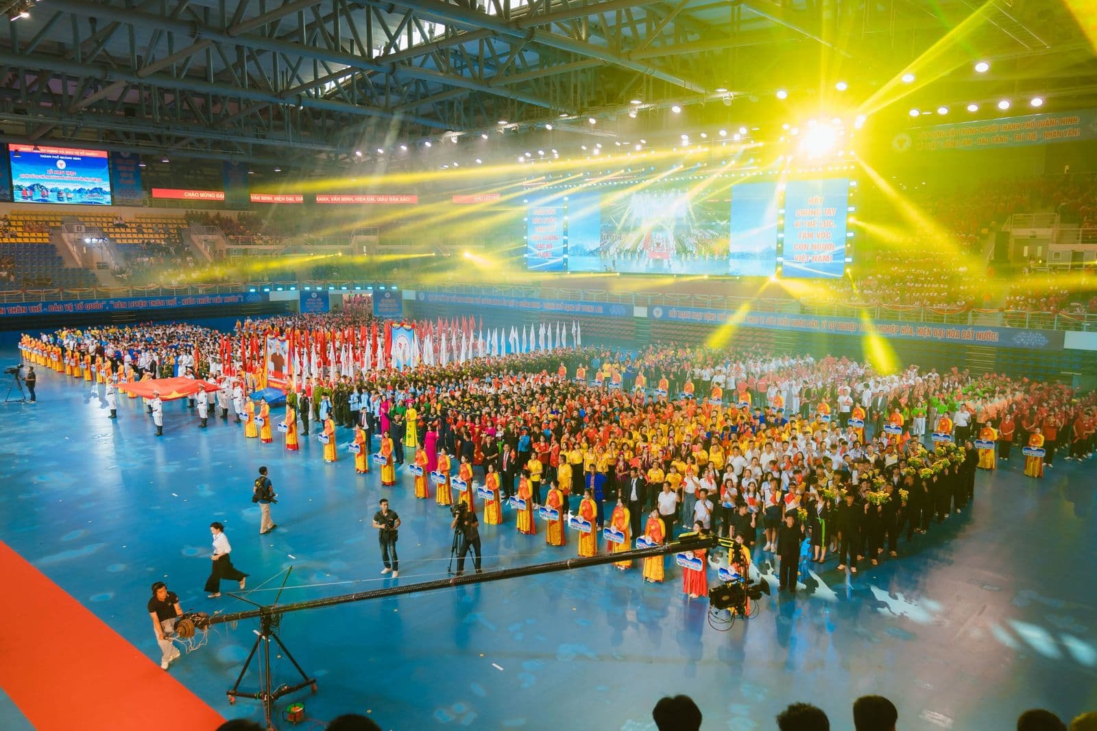 Các khối đứng kín sàn nhà thi đấu dưới dàn đèn beam vàng, màn hình LED và cẩu máy quay truyền hình