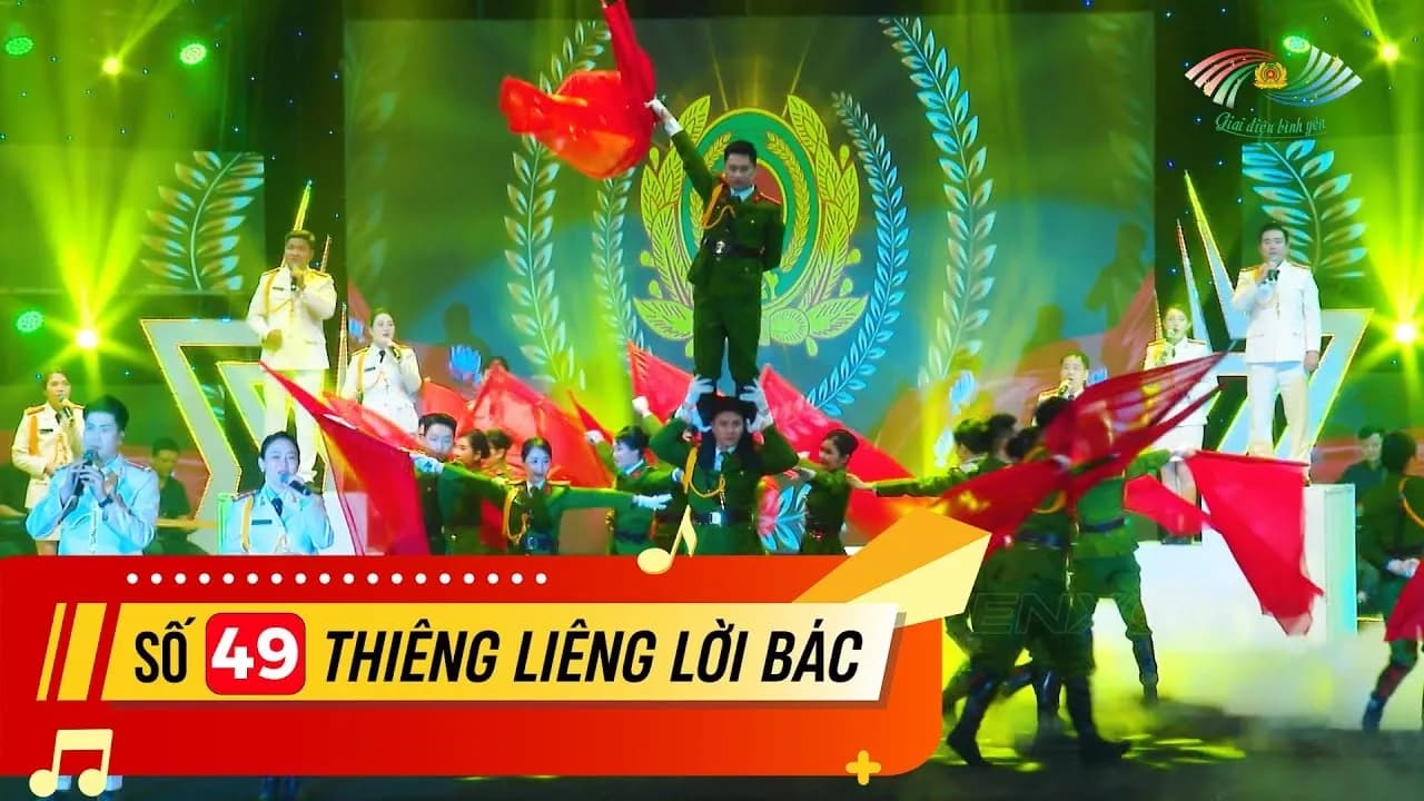 Tiết mục múa cờ trong chương trình Giai điệu bình yên số 49 “Thiêng liêng lời Bác”, nền màn hình LED hiện công an hiệu, đèn beam chiếu xiên và khói phủ sàn sân khấu